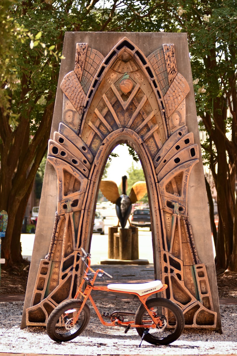 Super73 electric bike parked inside a sculptural stone archway in downtown Pensacola