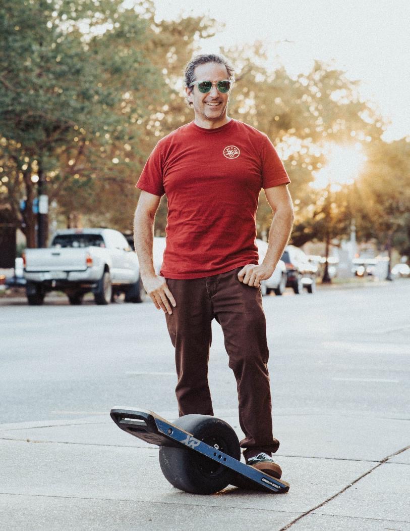 Rider posing with a Onewheel electric board on a downtown Pensacola street