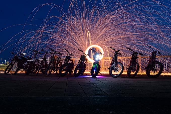 Row of electric bikes lit up by a spinning sparkler display at night