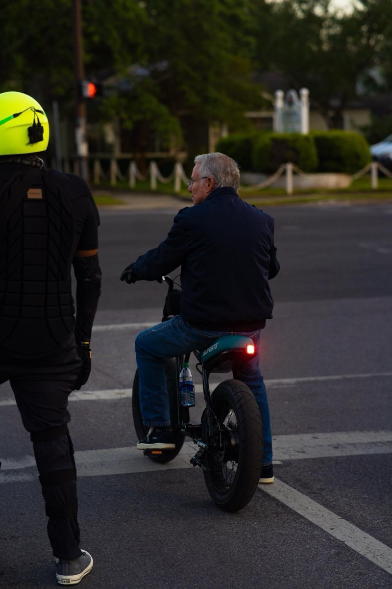 Rider crossing a downtown Pensacola street on a Super73 electric bike at dusk