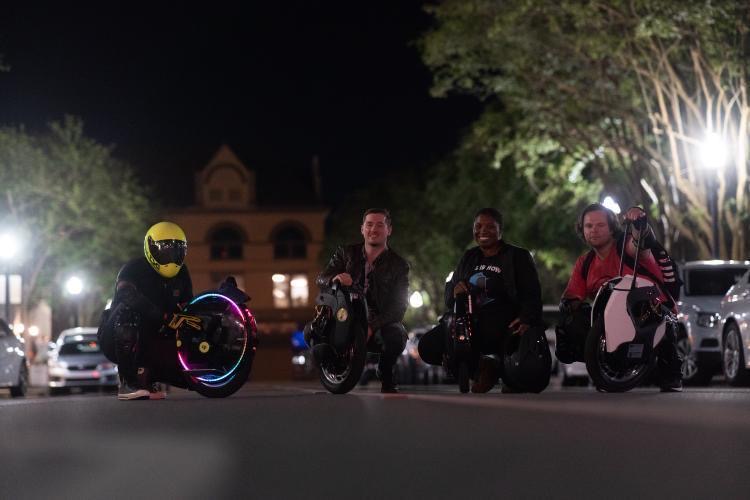 Group of riders with Onewheel electric boards on a downtown Pensacola street at night