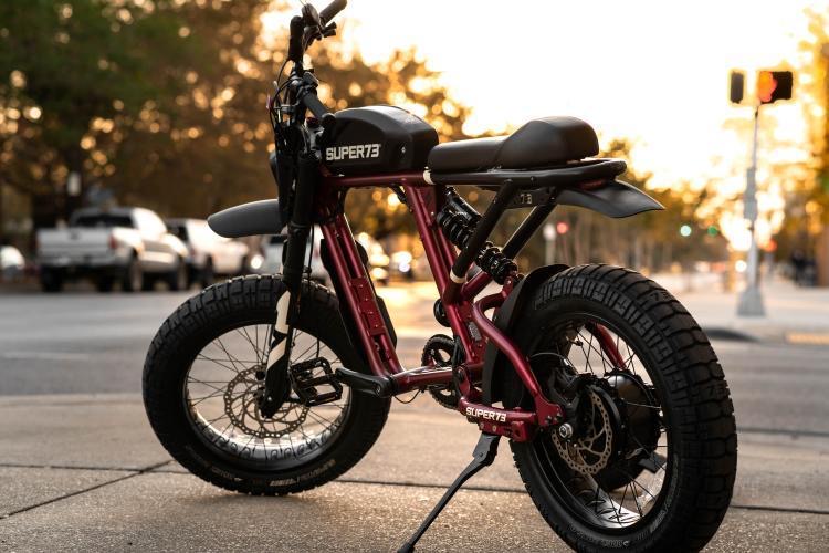 Super73 electric moped parked on a downtown Pensacola sidewalk at sunset