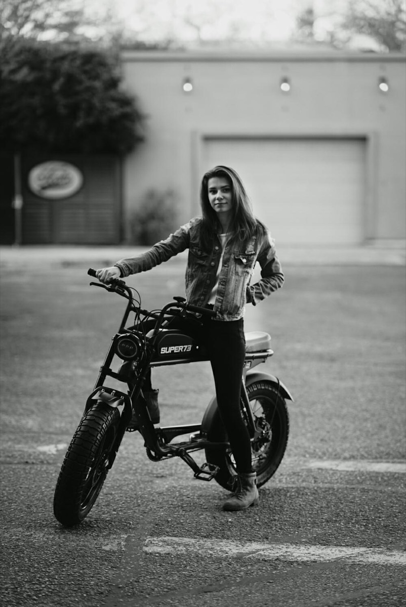 Rider standing with a Super73 electric bike in a downtown Pensacola parking lot