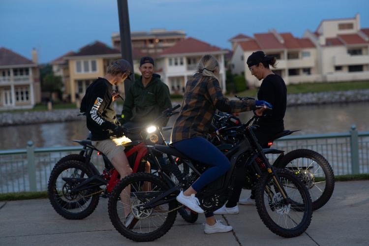 Group of riders with their electric bikes along the Pensacola waterfront at dusk